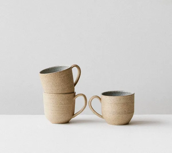 Three speckled beige ceramic mugs stacked