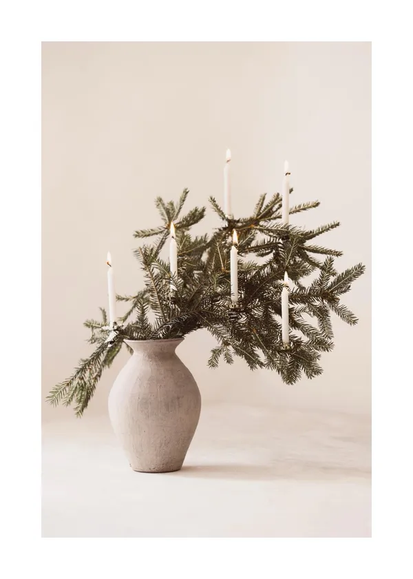The Ribbed Vase holding evergreen stems beside lit candles